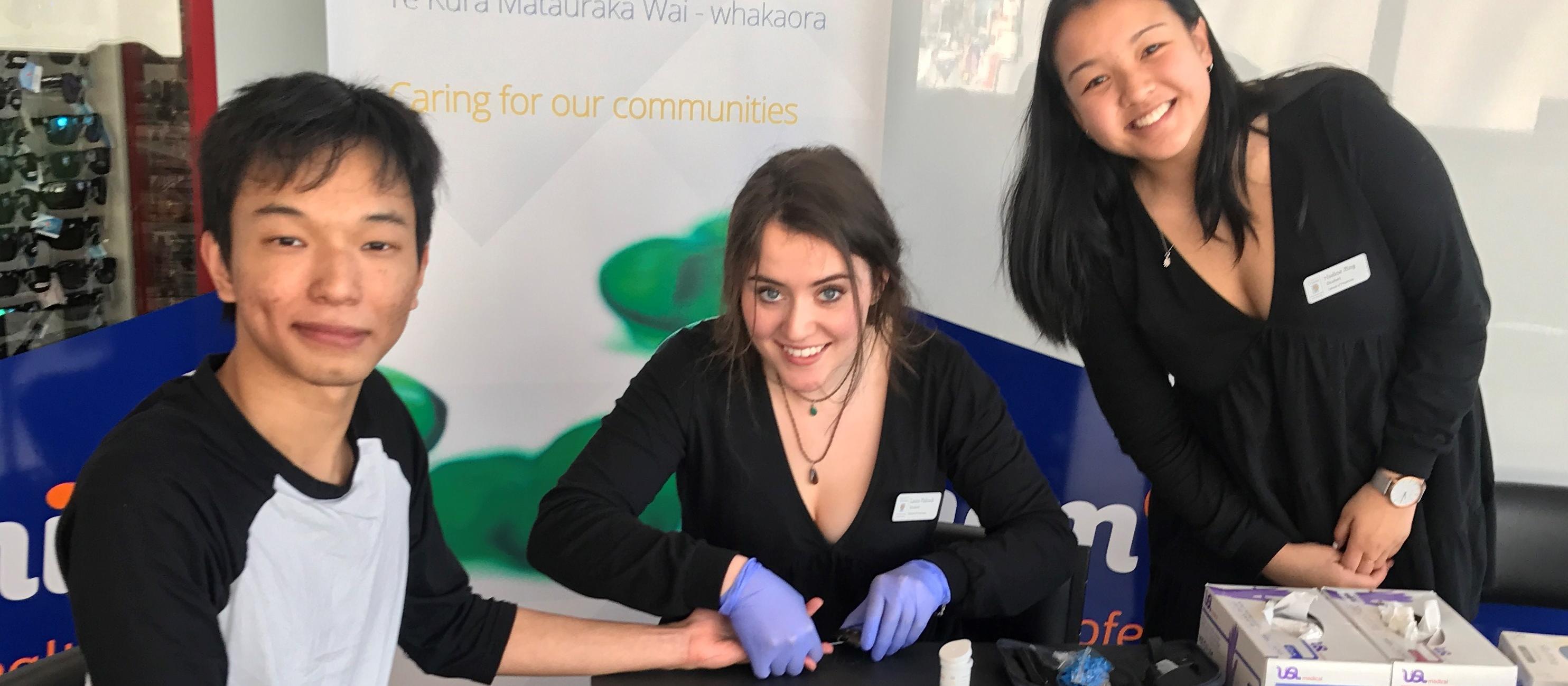 Otago pharmacy students Laura Pidcock (centre) and Nadine King offer a blood glucose test to Dunedin resident Van Chanusorn