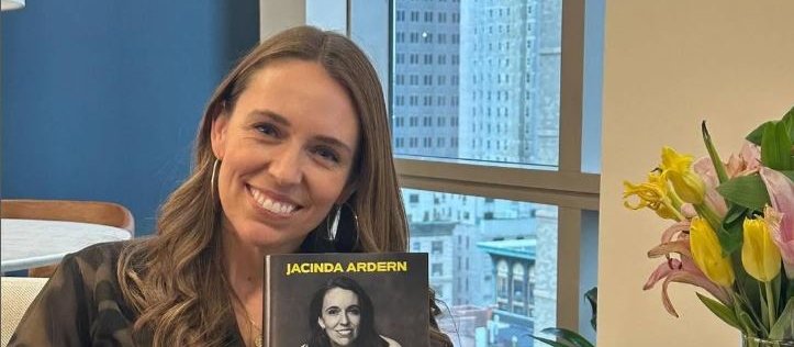 Jacinda Ardern holds a copy of her book, smiling at camera