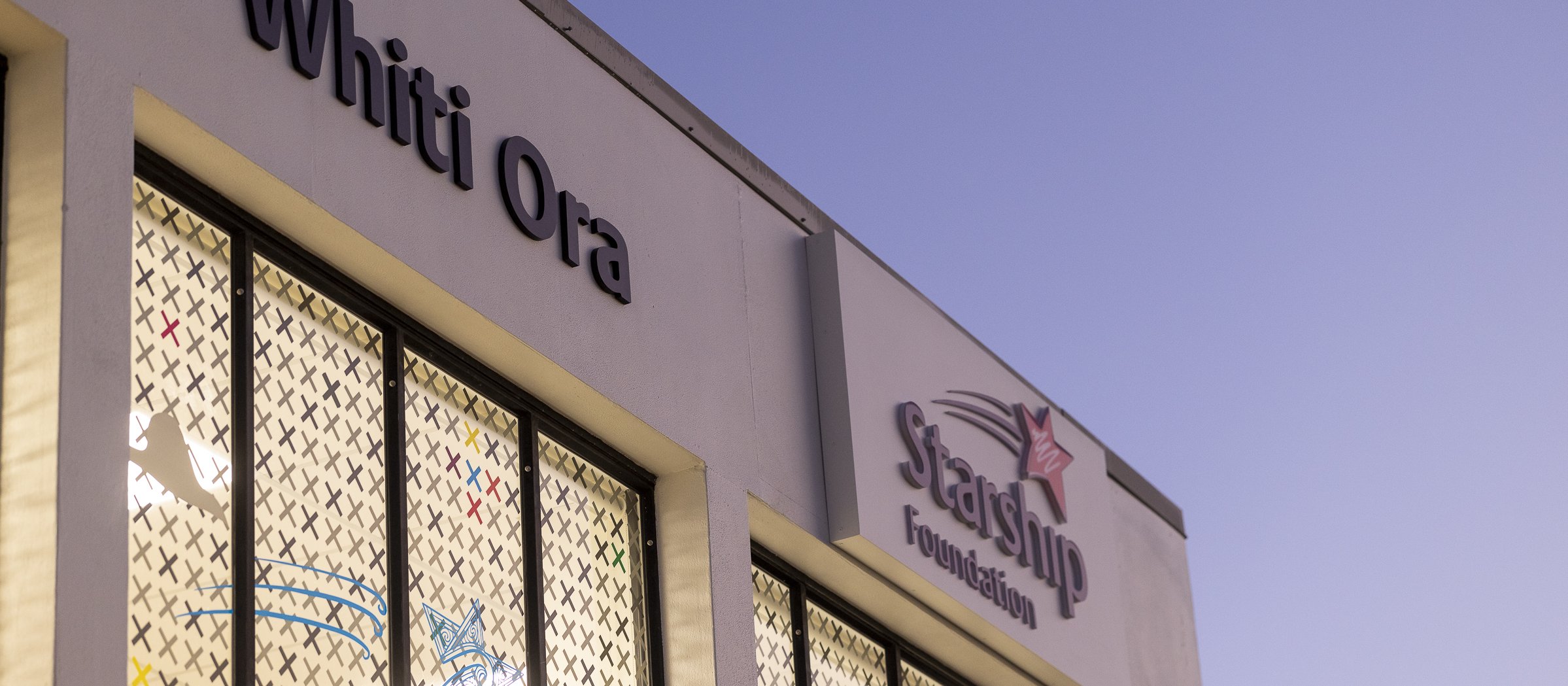 Image shows corner of building in dawn light, signage reads Whiti Ora, Starship Foundation