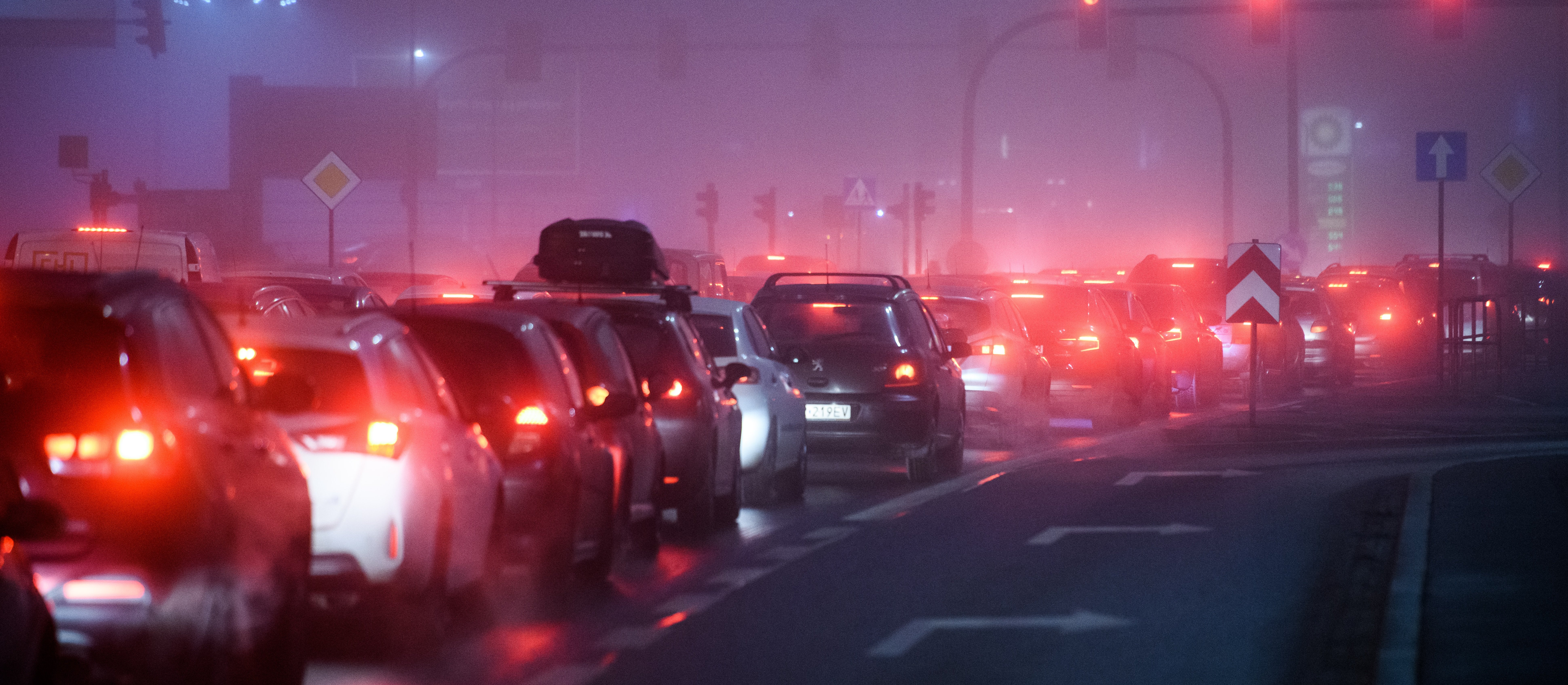 A line of cars in a traffic jam with smog haze