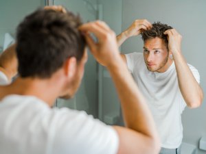 man checking hair in mirror