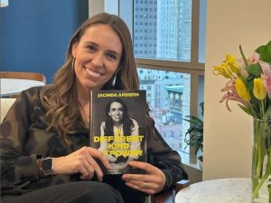 Jacinda Ardern holds a copy of her book, smiling at camera